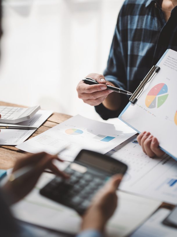 Young colleagues discuss business and analytical price charts using calculators and laptops to calculate financial, tax, accounting, statistics and analytical research ideas