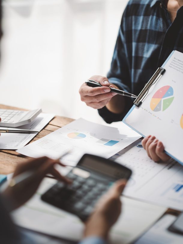 Young colleagues discuss business and analytical price charts using calculators and laptops to calculate financial, tax, accounting, statistics and analytical research ideas